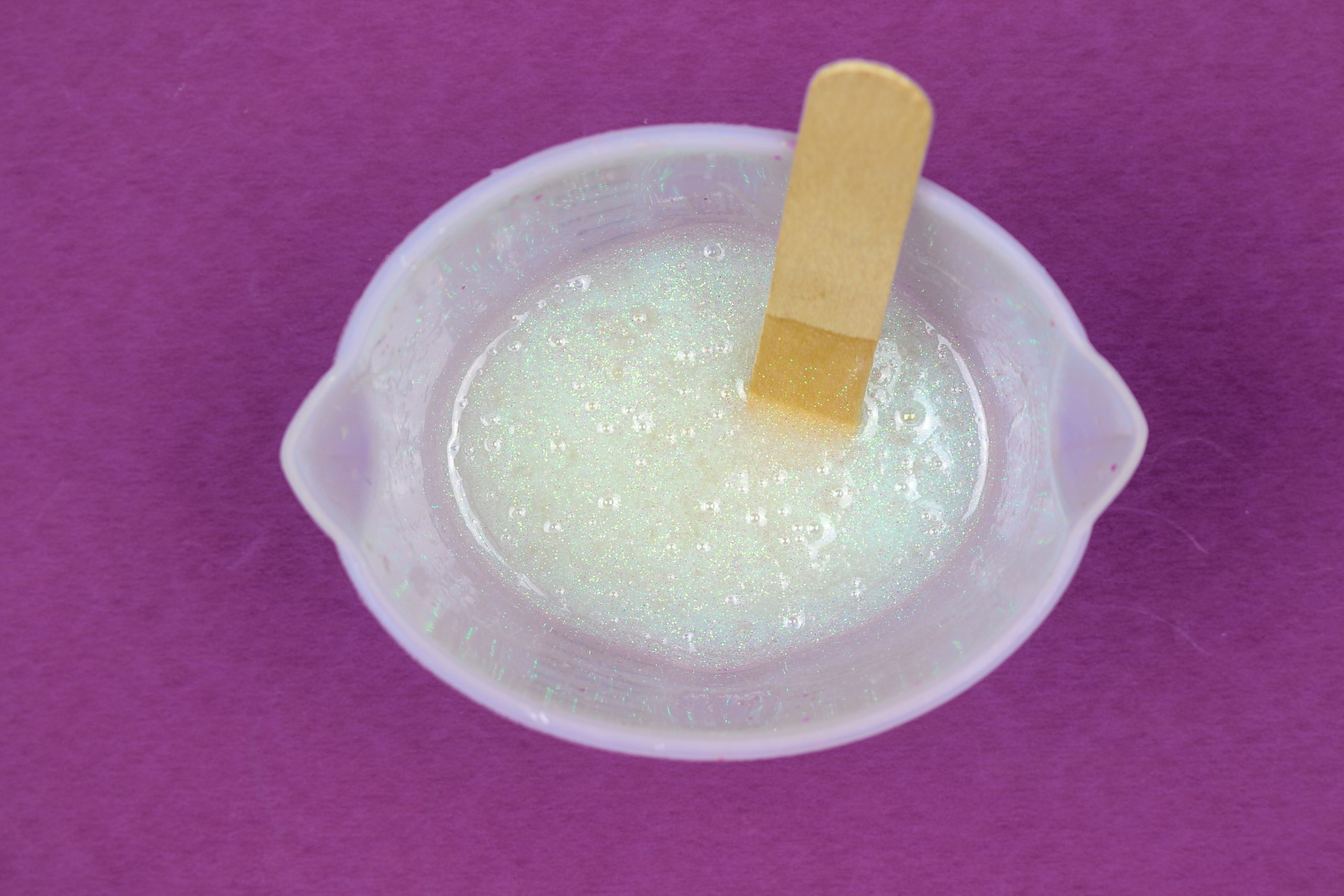 a silicone measuring cup filled with glittery white resin