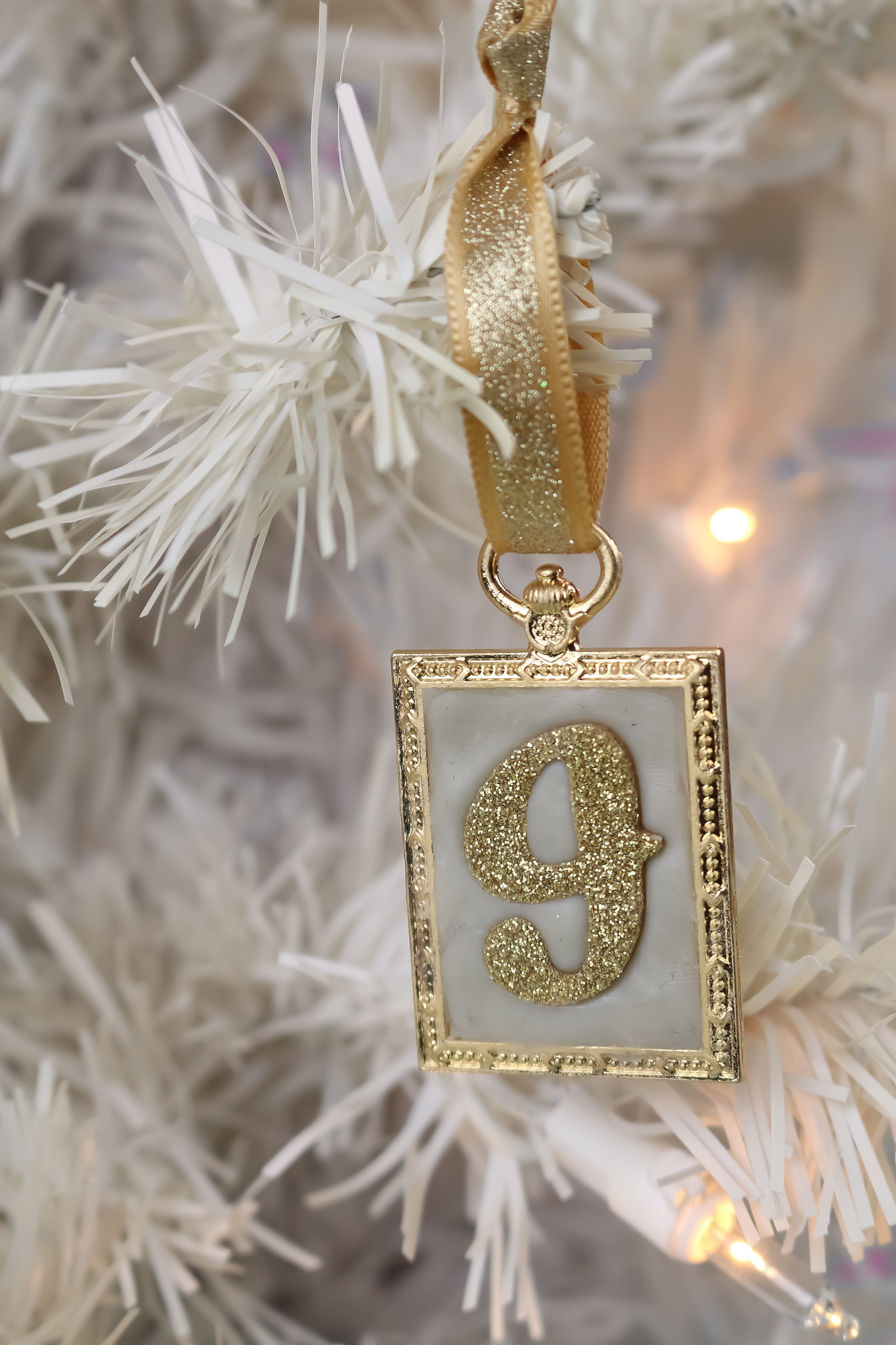 a letter J initial ornament hanging on a white tree