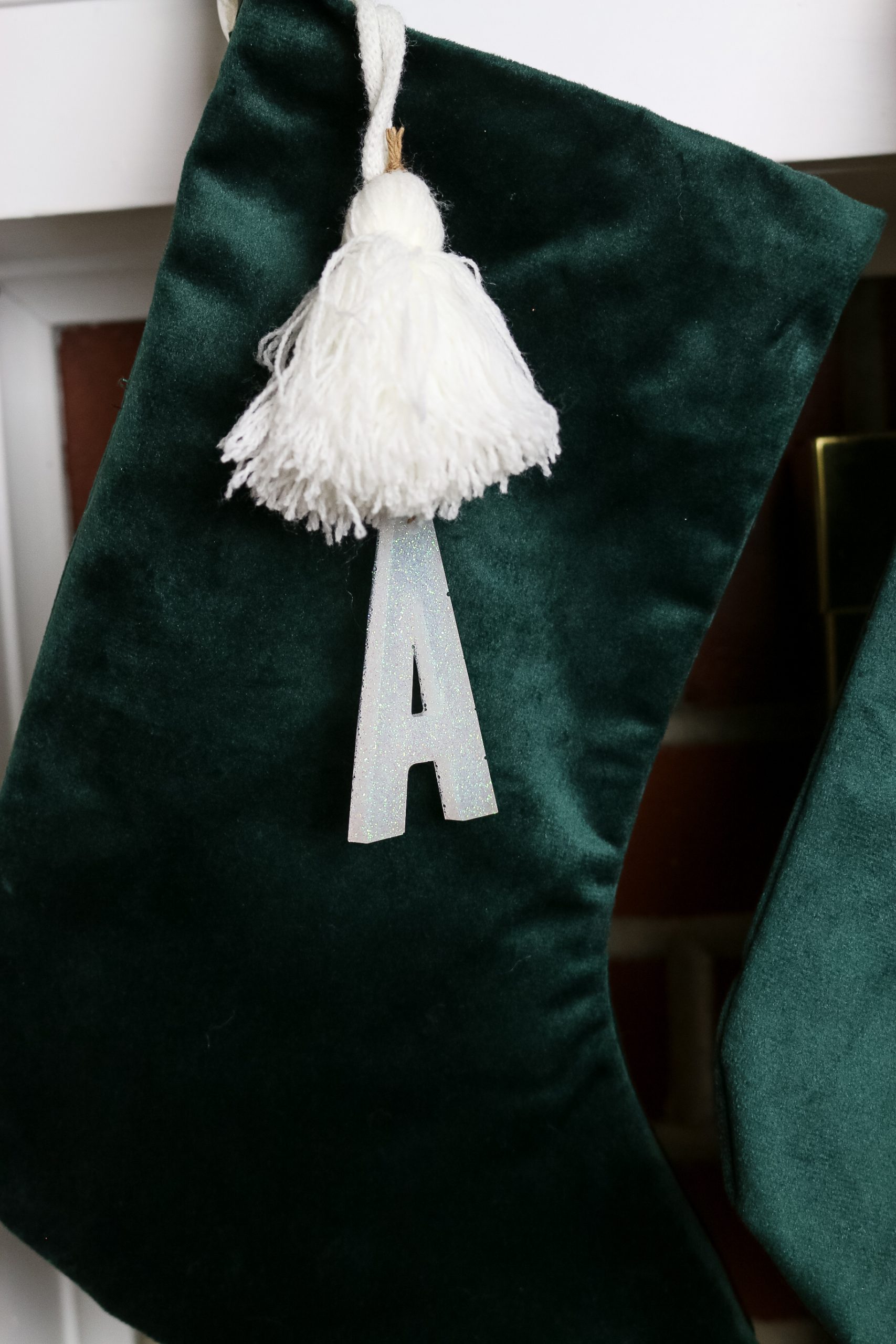 close up of a green velvet stocking with an A stocking markers hanging on a mantel
