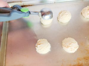 cookie scoop putting sugar cookie dough onto a baking sheet