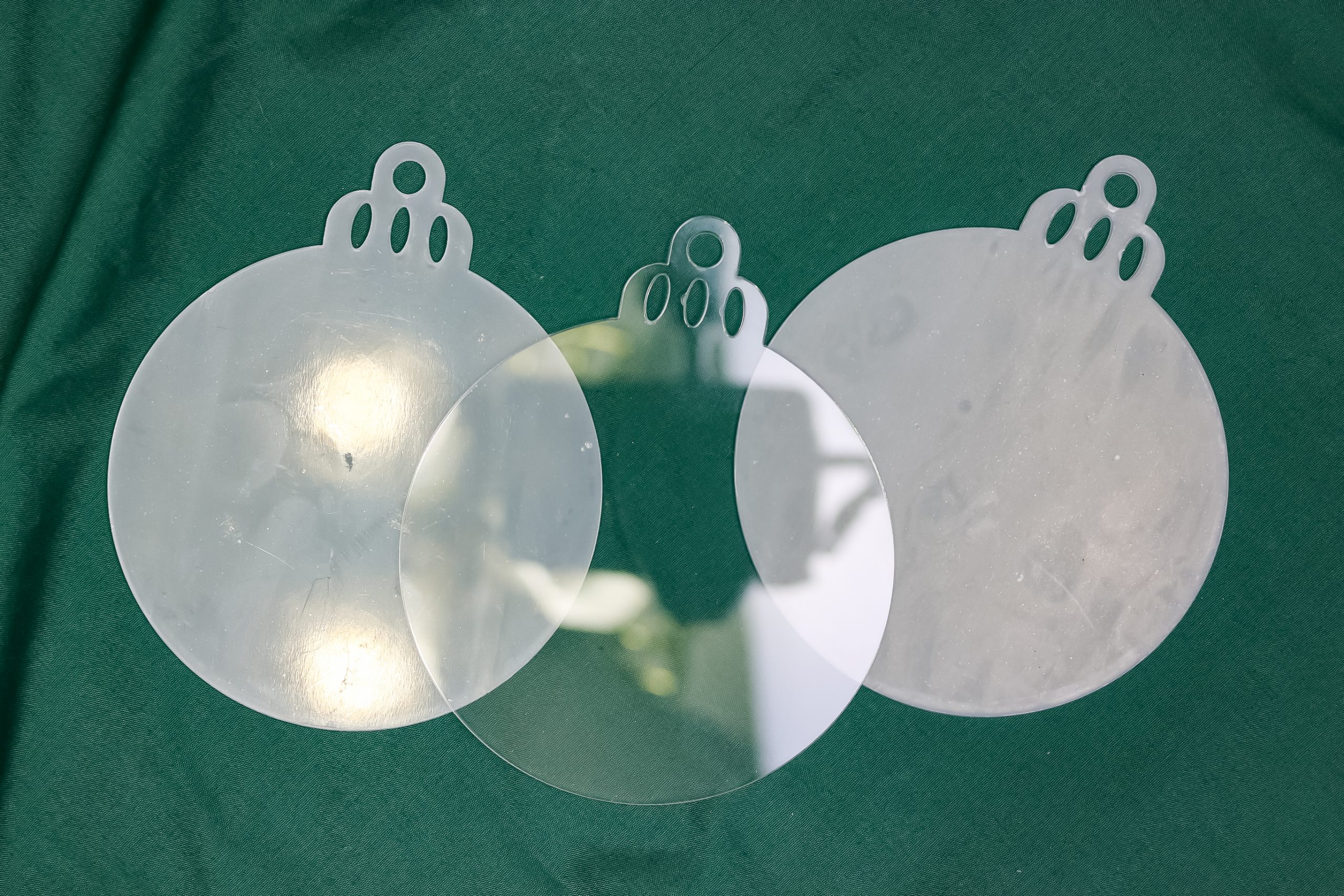 three acrylic ornament blanks on a green backround
