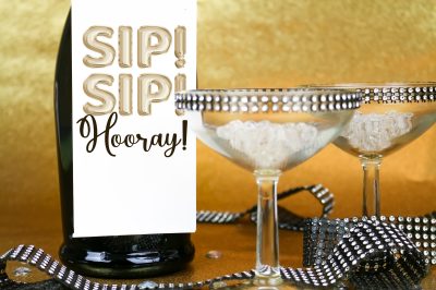 closeup Champagne bottle with Sip! Sip! Hooray! bottle tag on a gold background