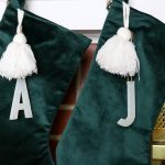 green velvet stockings with initial stocking markers hanging on a mantel
