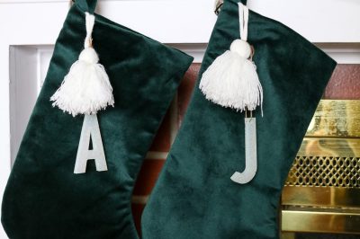 green velvet stockings with initial stocking markers hanging on a mantel