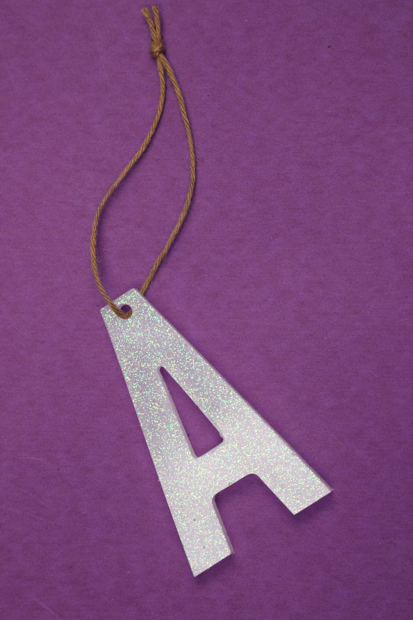 holding an A stocking marker made from resin with a length of twine as a hanger