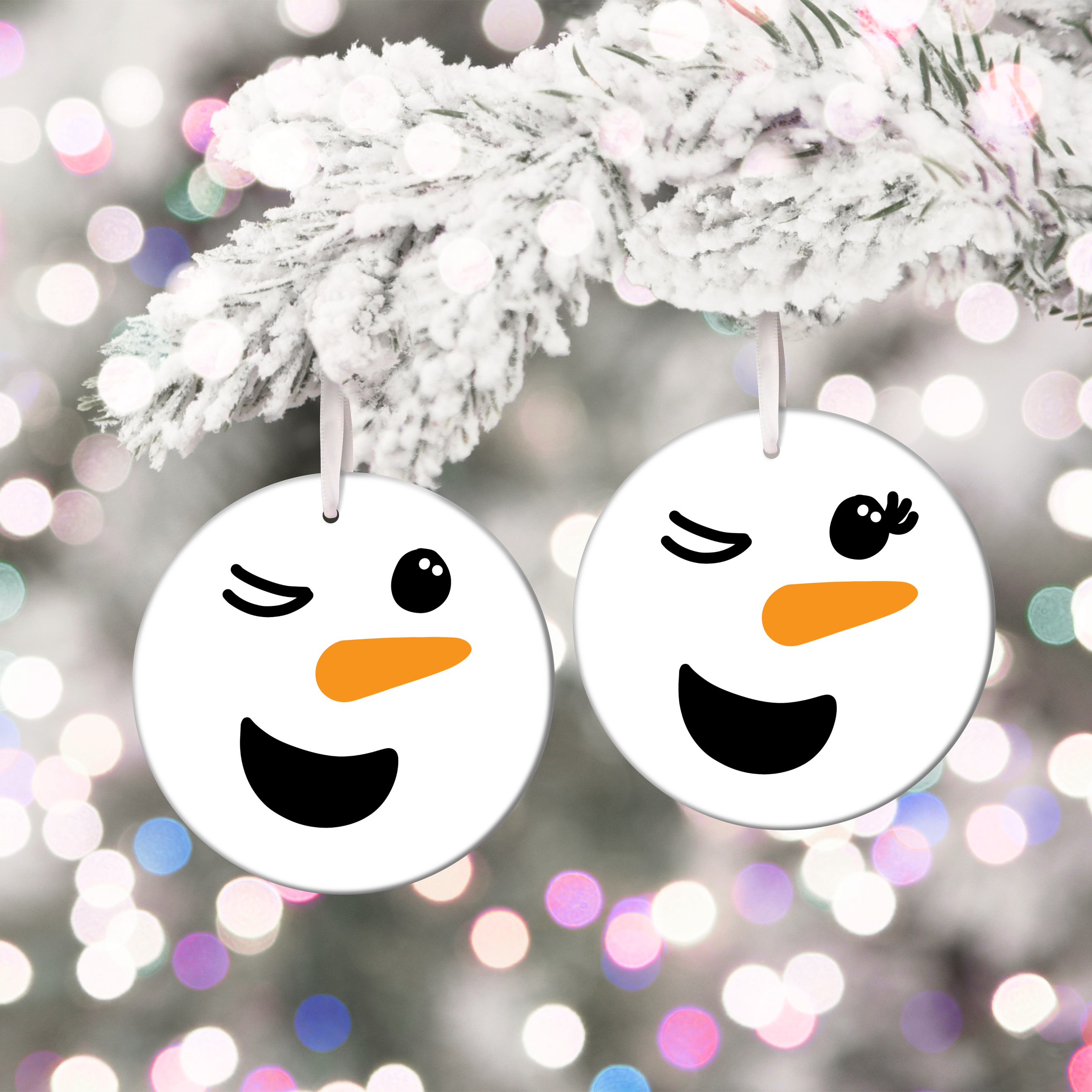 two winking snowman face ornaments on a white tree