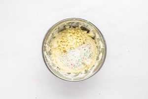 metal bowl containing cream cheese mixture and white chocolate chips