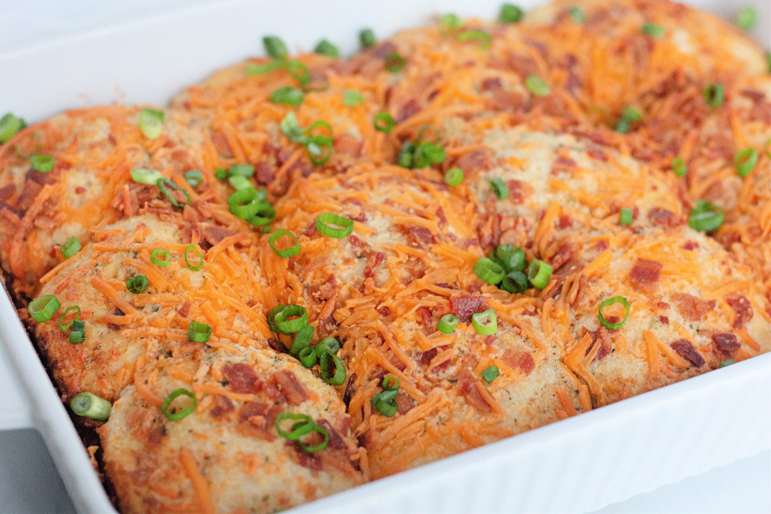 Baked biscuits topped with cheese, bacon, and green onions.