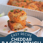 Two baked biscuits topped with cheese, bacon, and green onions on a plate.