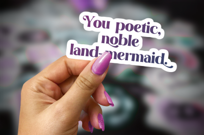 woman's hand holding a sticker that reads You poetic, noble land mermaid