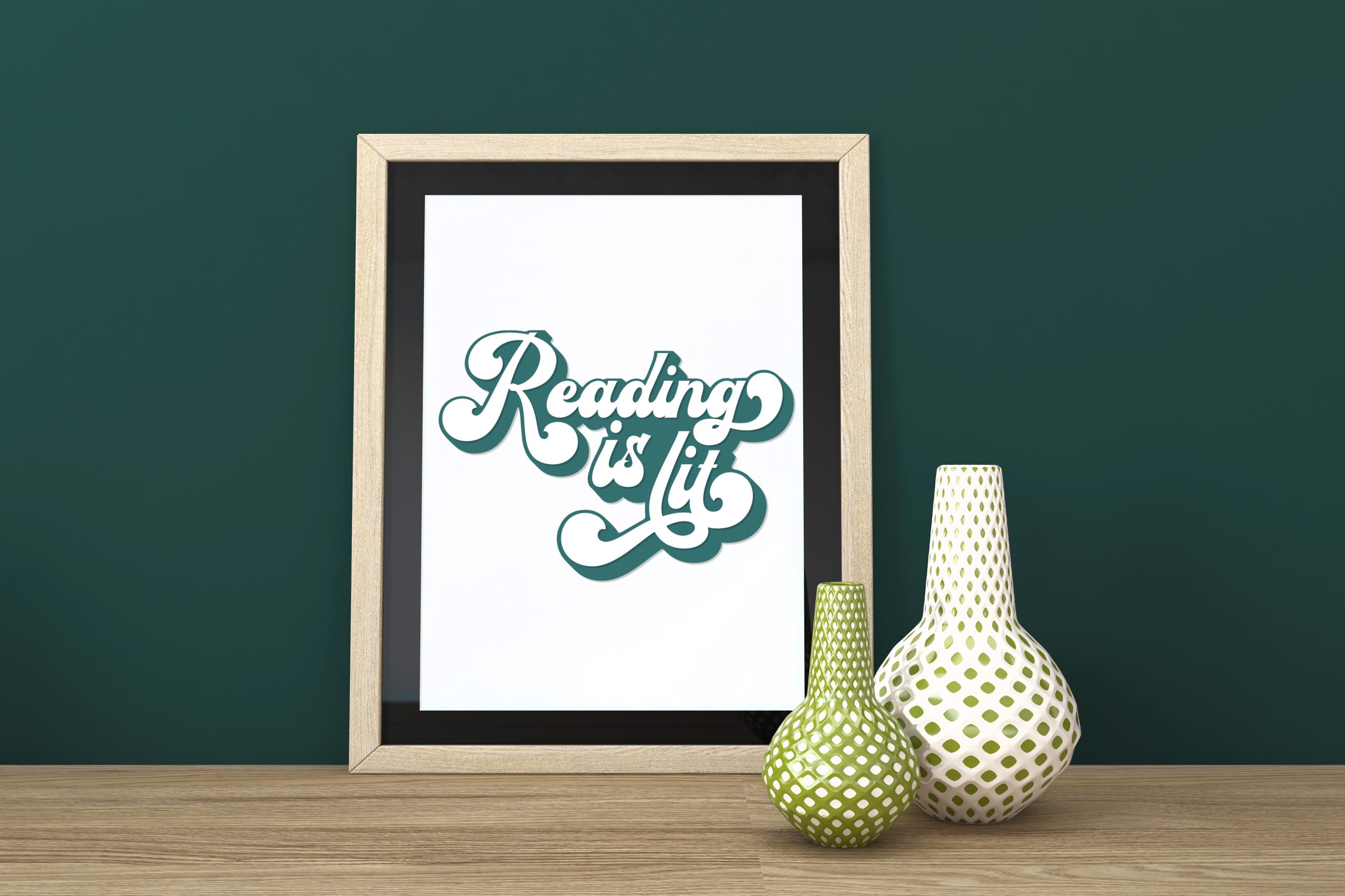 Framed Reading is Lit papercut design on a table near green vases
