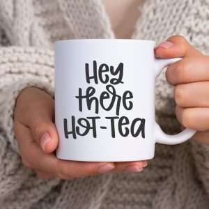 Hey There Hot-Tea SVG on a white mug that is held by a woman in a white sweater