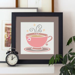 pink tea cup art in a black frame on a shelf