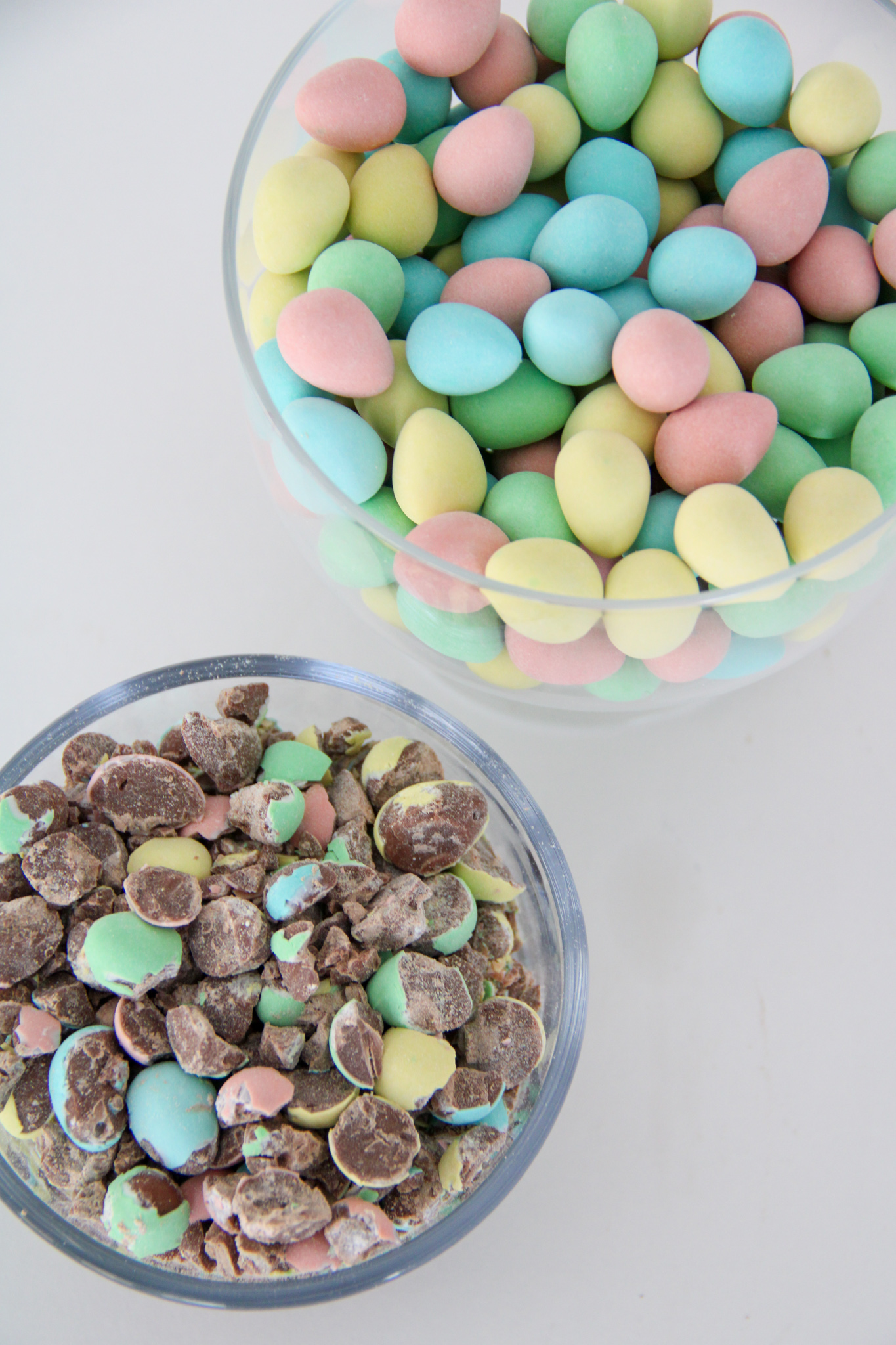 Two bowls of Cadbury Mini Eggs. One bowl has whole candies and one bowl holds crushed candies.
