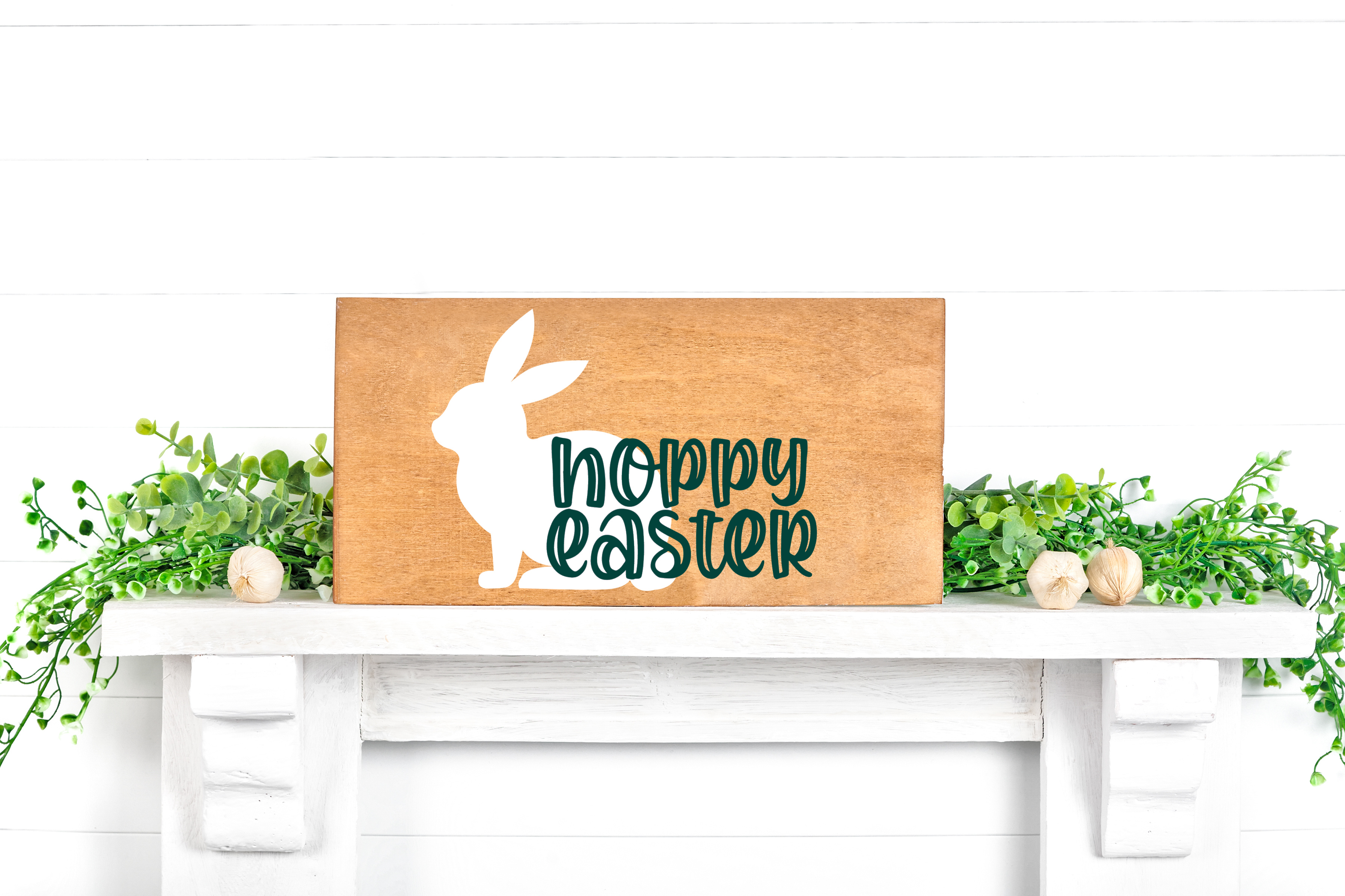 Wood sign with Hoppy Easter SVG design sitting on a white wall shelf