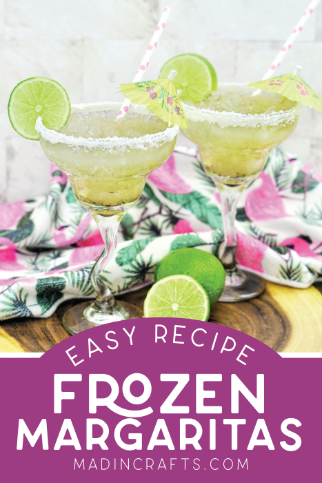 Two frozen lime margaritas with salt rims have been garnished with lime and a small umbrella.