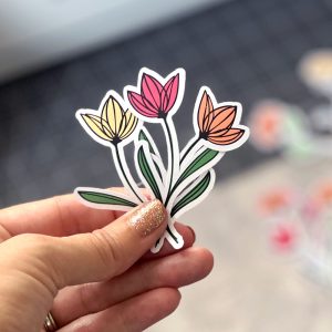 White woman's hand holding stickers made with flower SVGs