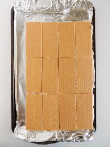 Graham cracker ice cream sandwiches on a baking tray lined with foil