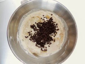 Metal mixing bowl full of mascarpone mixture and topped with mini chocolate chips