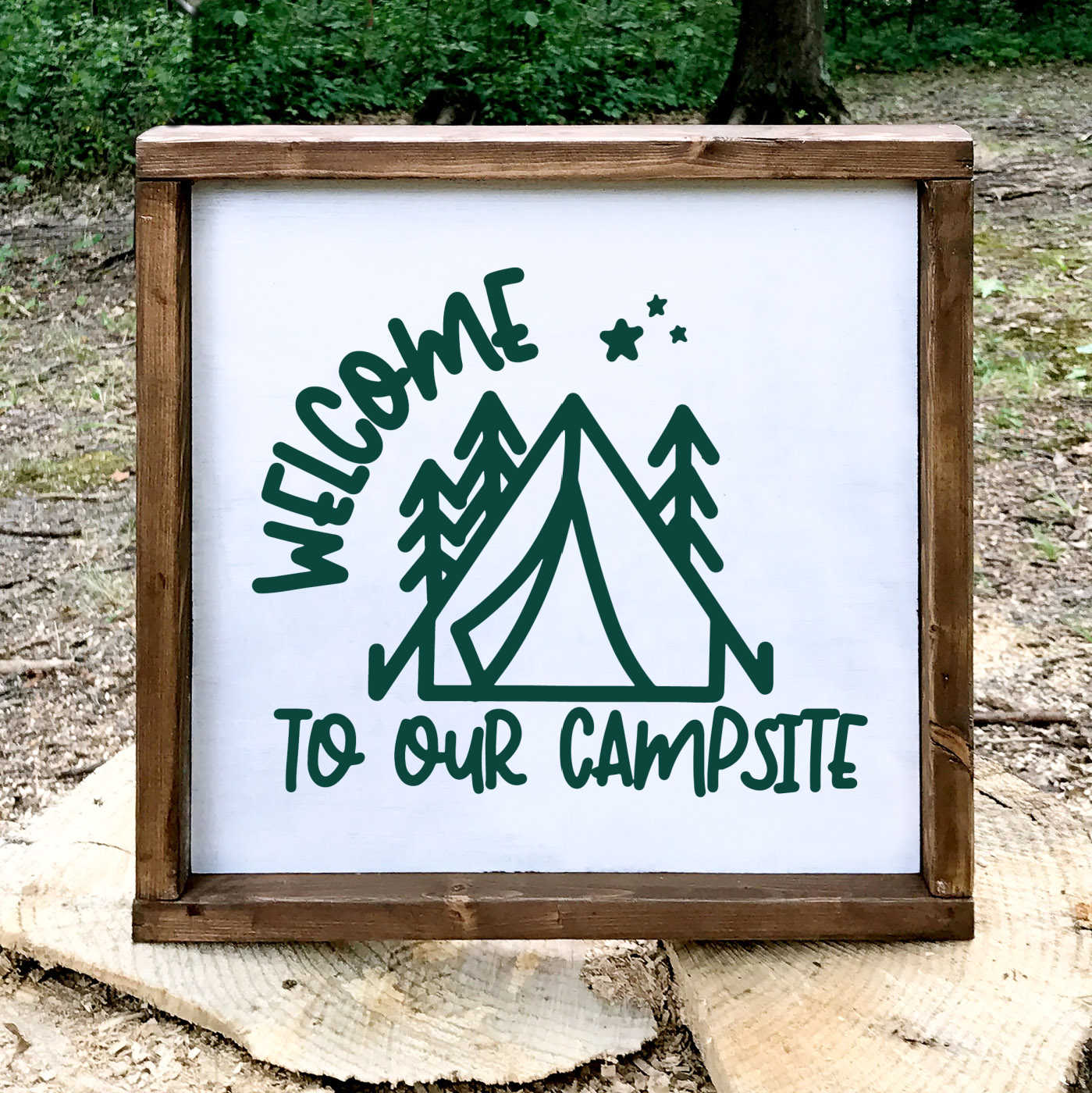 Square wood frame that contains a white sign with Welcome to Our Campsite design