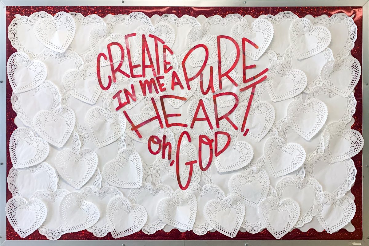 Heart themed bulletin board with white heart doilies and a bible verse in a heart shape