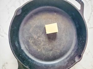 cast iron skillet with pat of butter in it