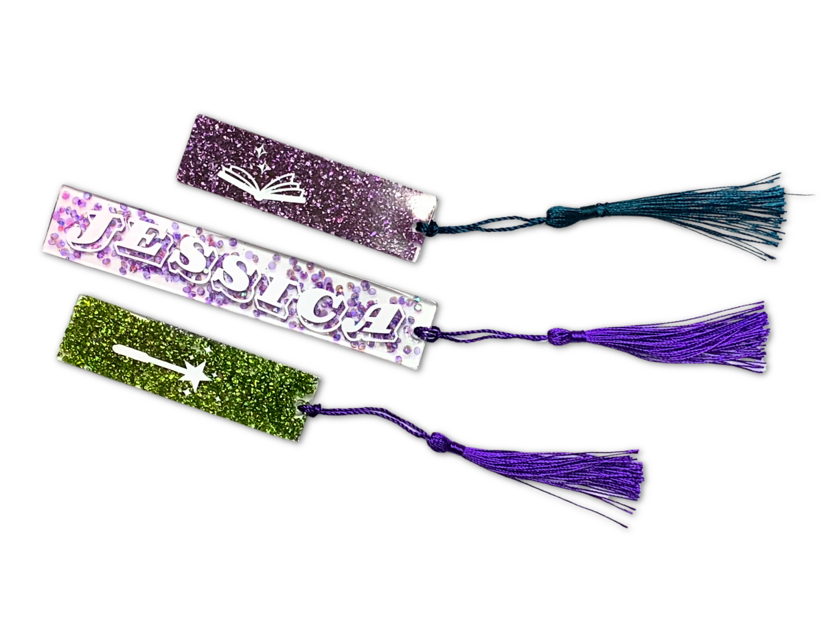 Three homemade resin bookmarks with tassels on a white background