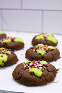 Fresh baked chocolate cookies with green slime frosting and Halloween sprinkles