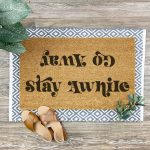 Doormat that says Stay Awhile in one direction and Go Away in one direction