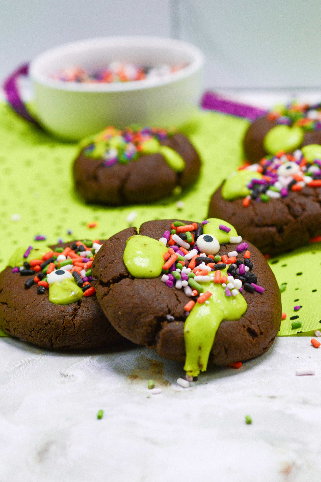 Close up of chocolate cookie with green slime frosting and Halloween sprinkles