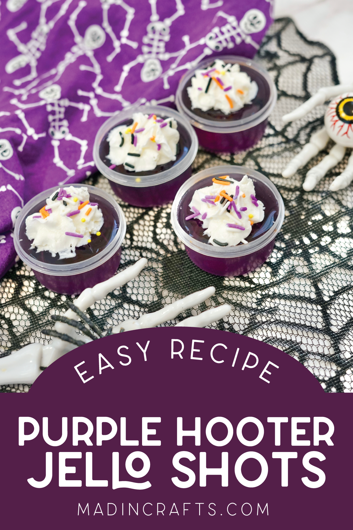 purple jello shots topped with whipped cream near Halloween decor