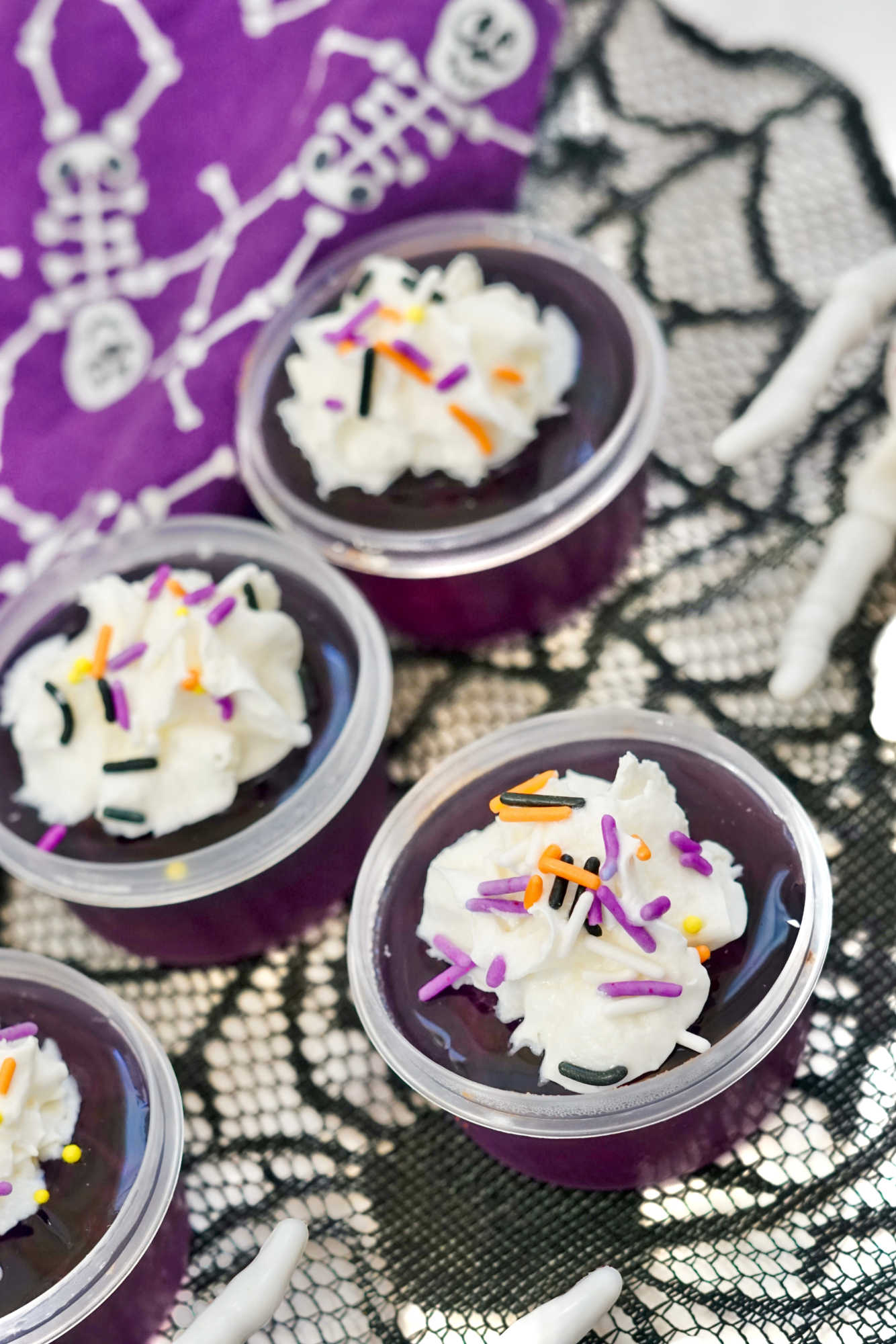 purple jello shots topped with whipped cream and sprinkles