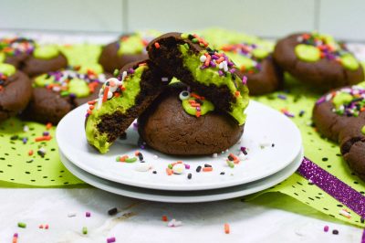 Plate of chocolate cookie with green slime frosting and Halloween sprinkles
