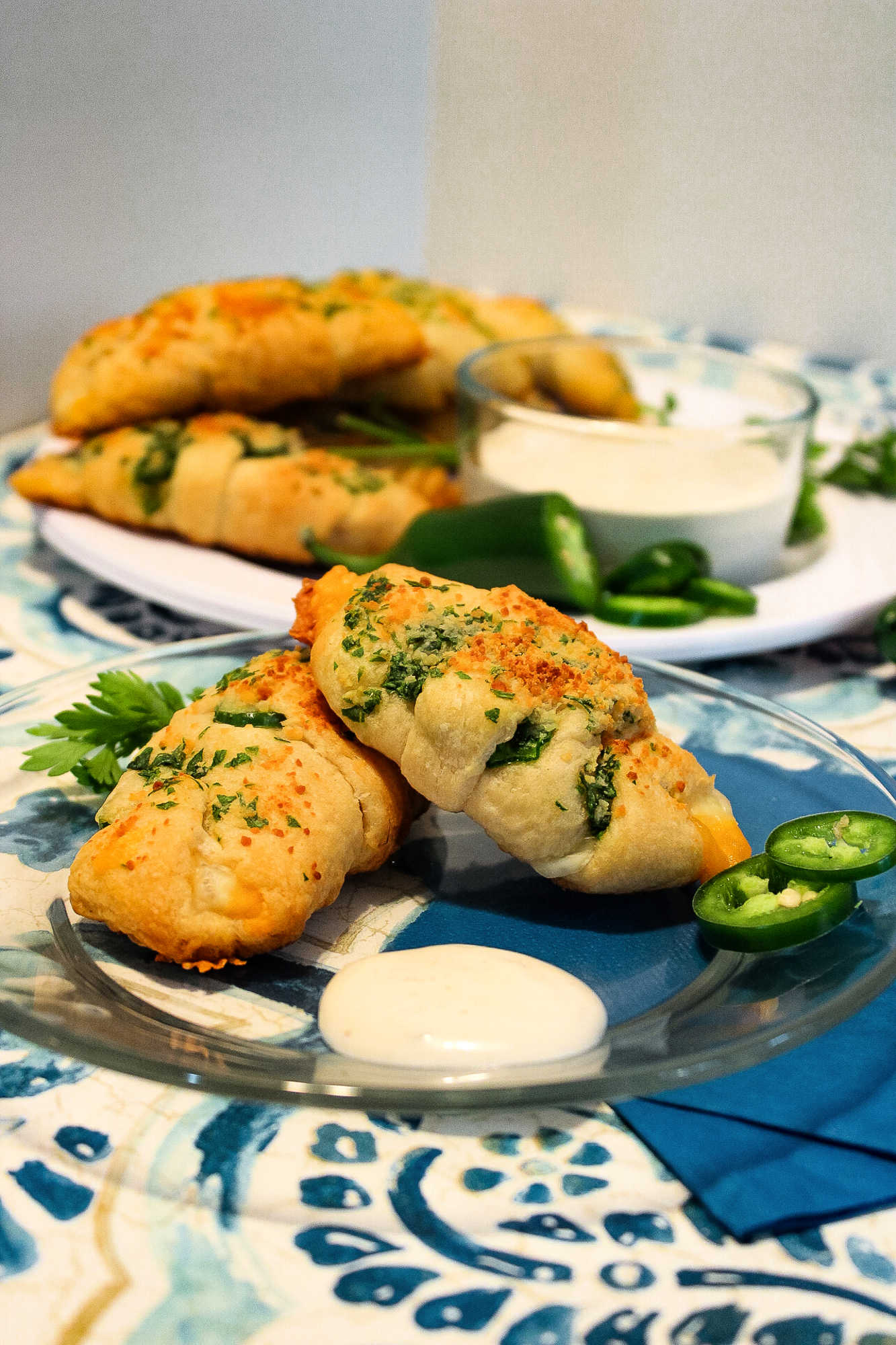 two cheesy jalapeno crescent rolls on a clear glass plate with ranch