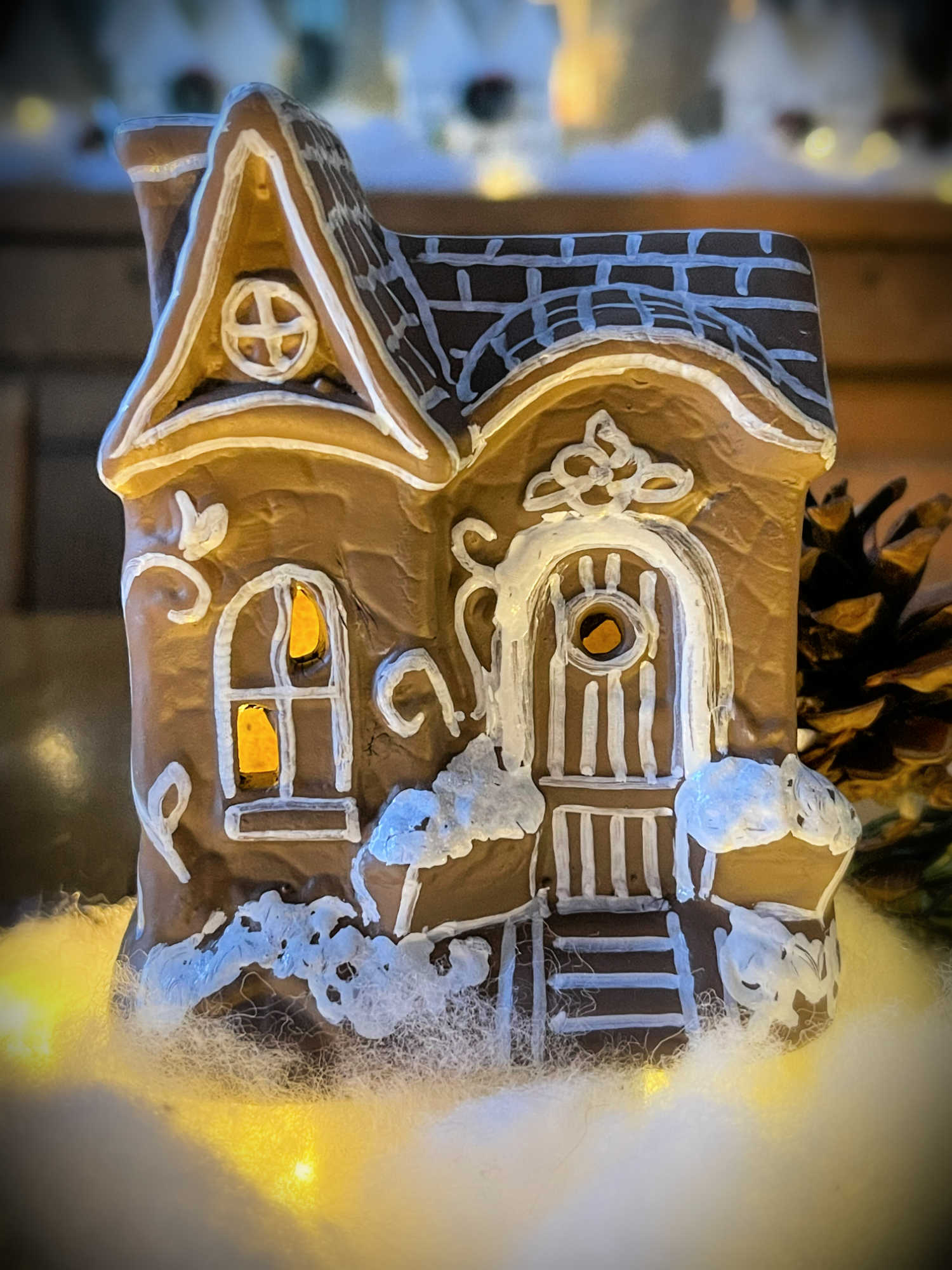 close up of a fairy house painted to look like gingerbread and lit with fairy lights