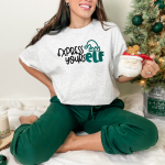 White woman wearing a White shirt with Express YoursELF design and holding a Santa mug
