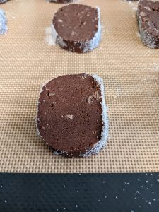 slices of salted chocolate shortbread cookie dough on a silicone baking sheet