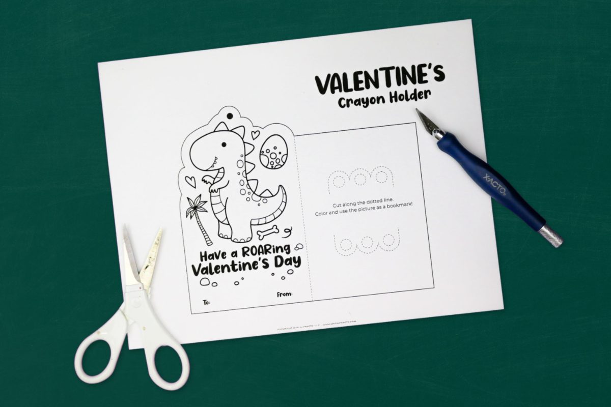 printable dinosaur valentine on a green backrground near a craft knife and scissors
