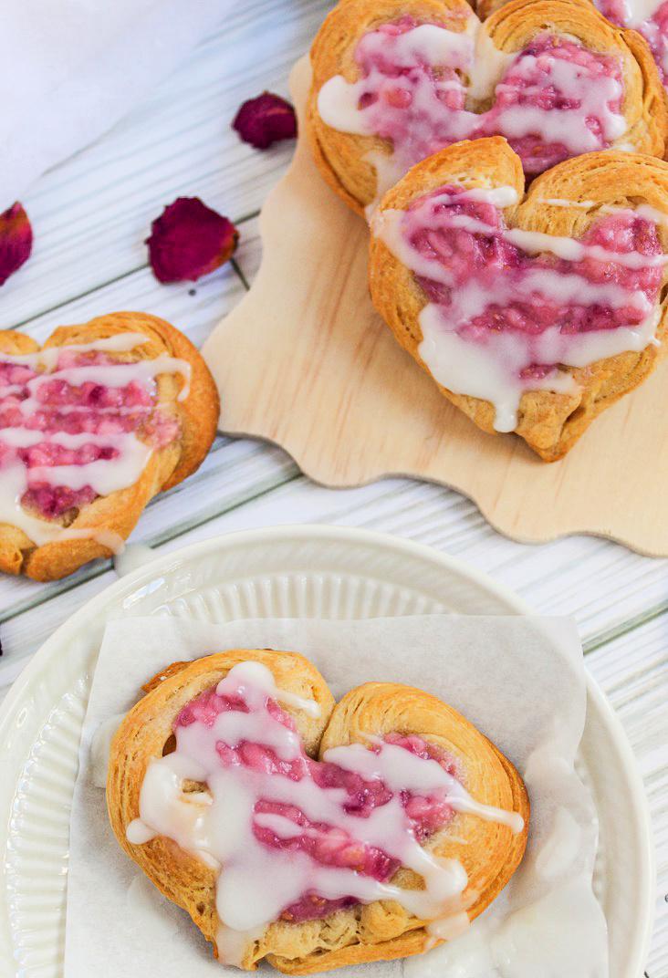 heart-shaped danish pastry on a plate near rose petals