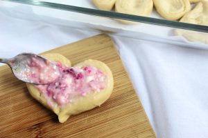 spooning raspberry cream cheese mixture onto heart shaped crescent rolls