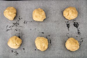 coconut cookie dough balls on a parchment lined baking sheet