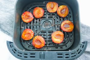air fryer tray holding eight cooked peach halves