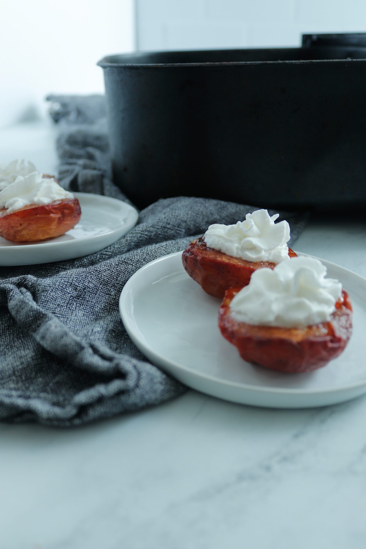 white plate of 2 air fried peaches topped with whipped cream