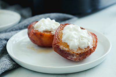 close up side view of air fried peaches topped with whipped cream