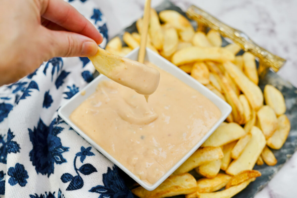 woman's hand dipping a french fry into homemade In-N-Out sauce