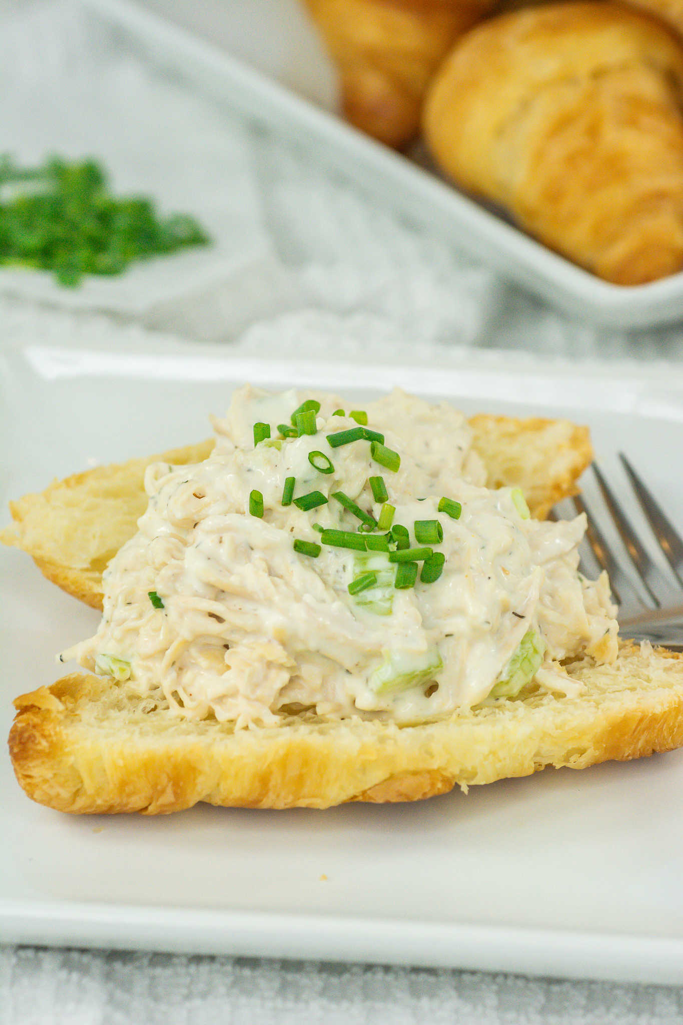 Side view of open faced chicken salad sandwich on a croissant