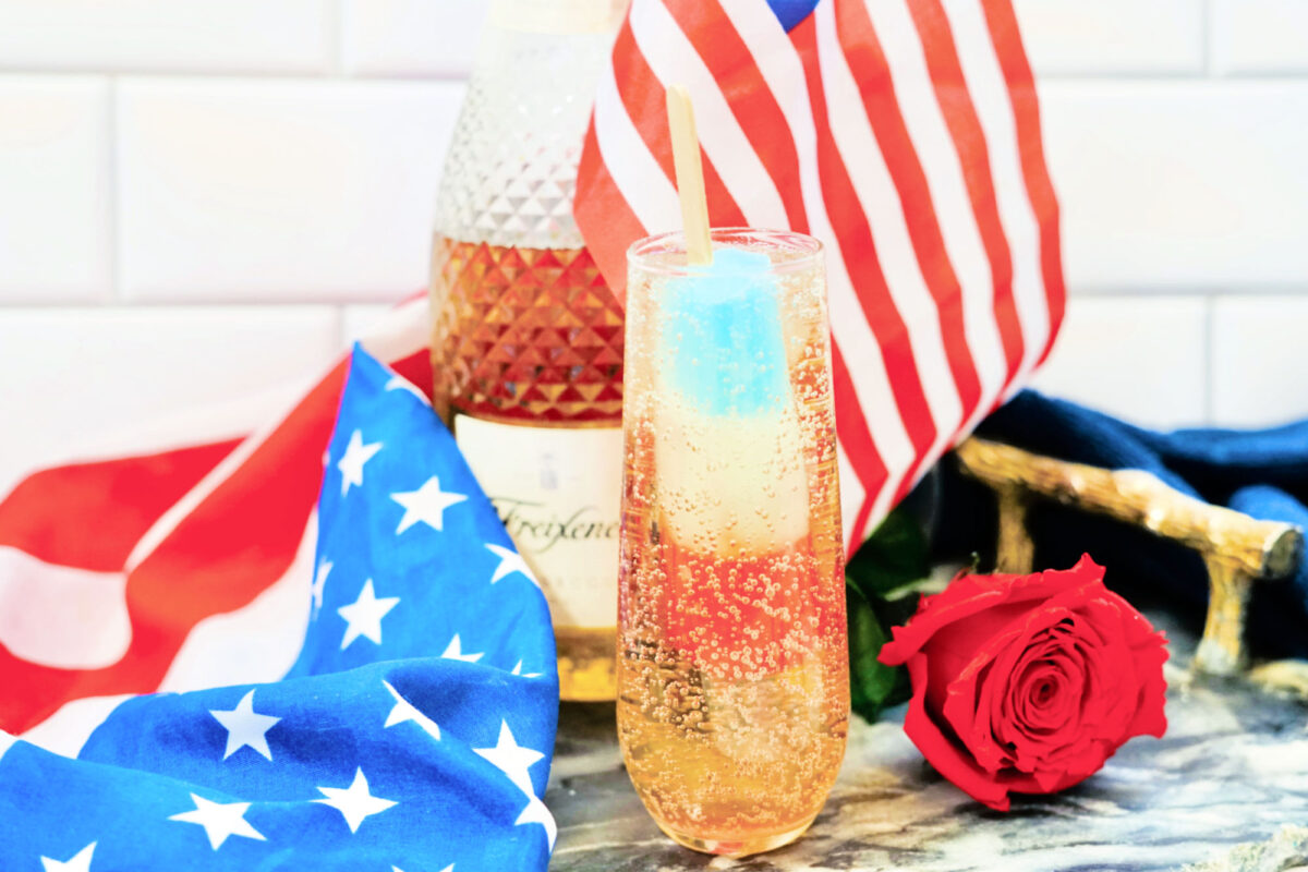 a bomb pop in a flute of sparkling wine near fourth of july decor