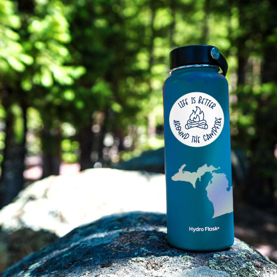 Life is Better Around the Campfire sticker on a waterbottle in the woods