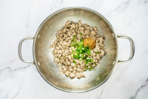 top view of ground turkey, green onion, and garlic in a wok