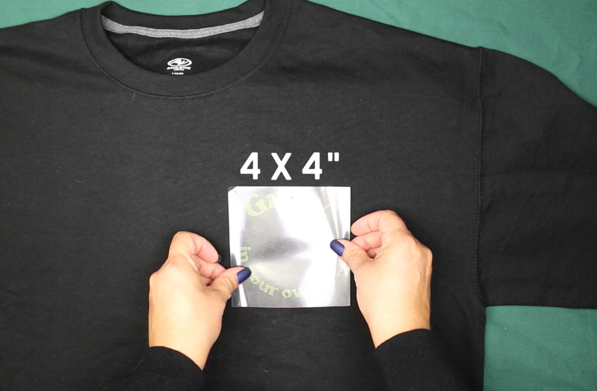 woman's hands placing iron-on vinyl on a black shirt